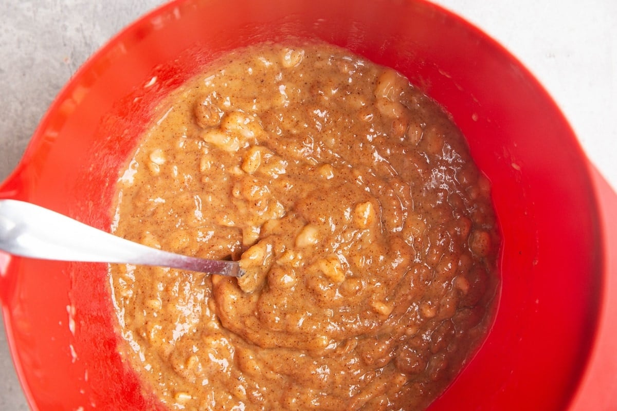 Mashed bananas, almond butter and pure maple syrup mixed together in a mixing bowl in a creamy substance.