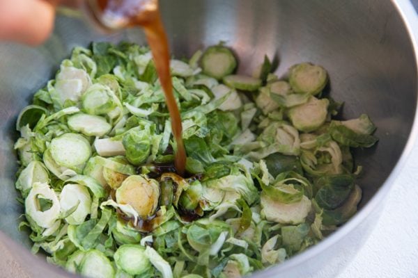 Pouring the dressing into a large mixing bowl with the shaved brussel sprouts.