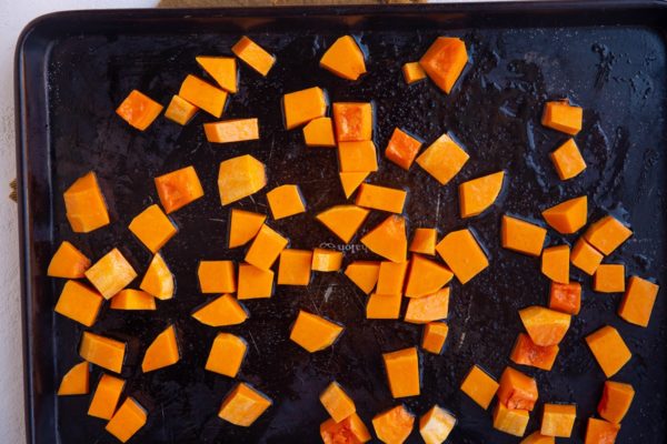 Baking sheet with raw butternut squash on top, ready to go into the oven.