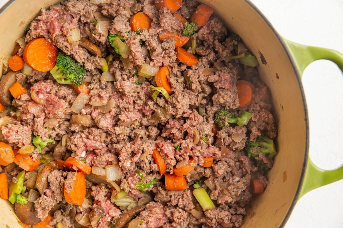 Ground beef cooking with vegetables in a large stock pot.