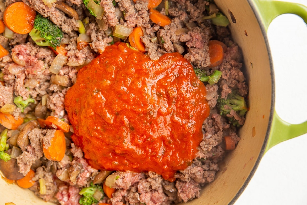 Tomato sauce on top of meat mixture, ready to be stirred in.