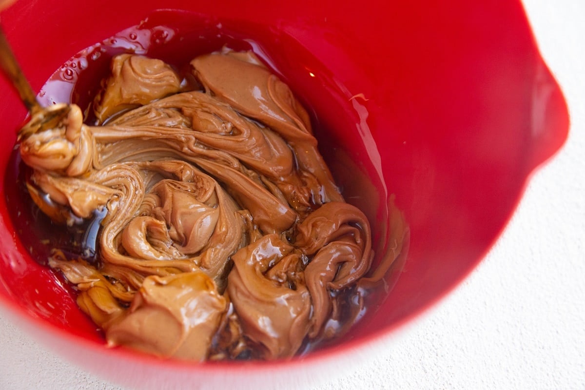 Mixing wet ingredients in a mixing bowl to make oatmeal peanut butter cookies