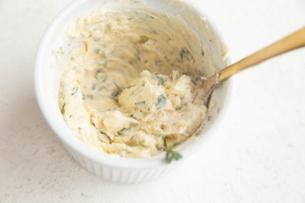 Butter, garlic, and fresh herbs combined in a small bowl to make compound butter for the best prime rib.