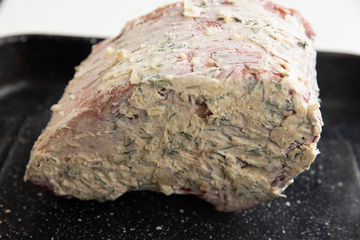 Prime rib rubbed in garlic butter sitting on a baking sheet.