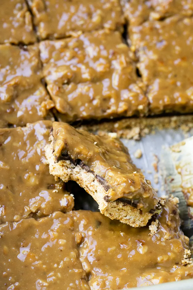 Paleo Samoa Cookie Bars cut into squares and one with a bite taken out.
