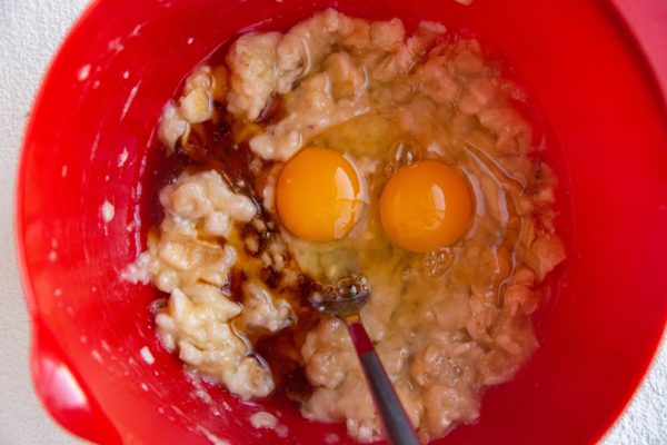 Mashed bananas, maple syrup and eggs in a mixing bowl.