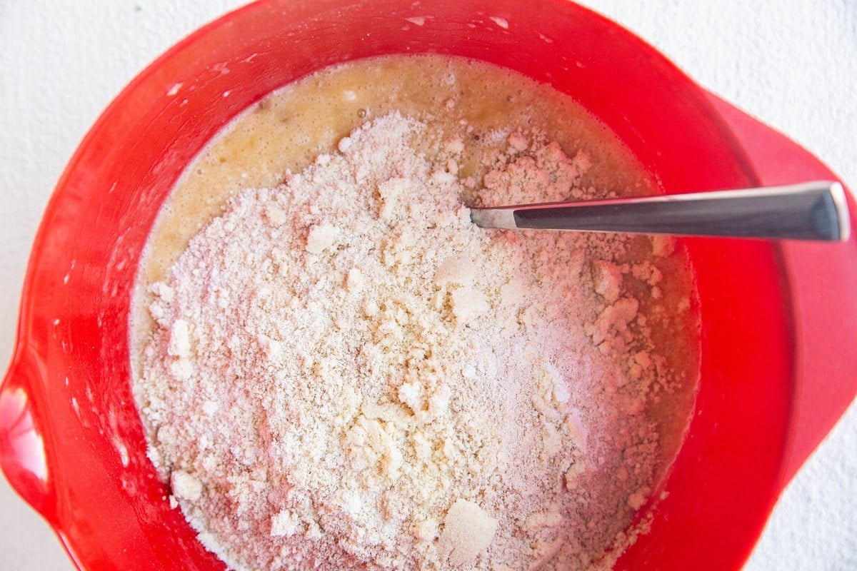Mixing bowl with wet ingredients and dry ingredients sitting on top, waiting to be mixed in.
