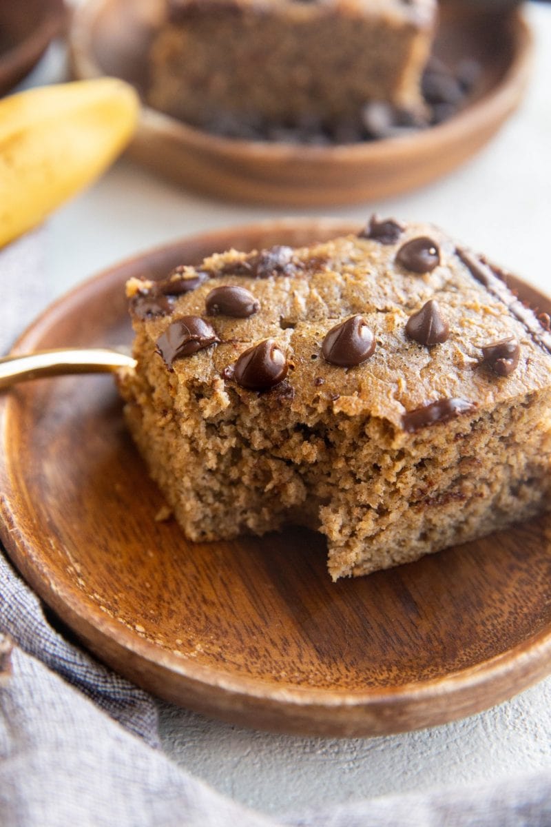 Slice of blended banana baked oats with a bite taken out on a wooden plate.