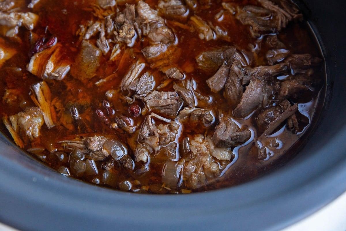 Shredded beef in a slow cooker in chipotle pepper sauce.