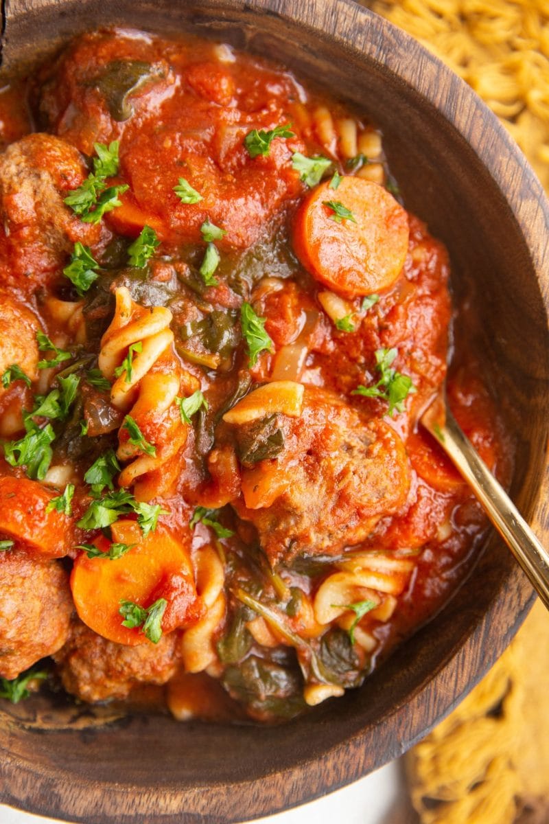 Close up photo of wooden bowl of Italian Meatball Soup.