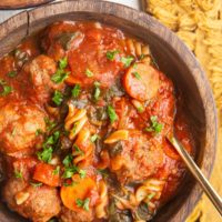 Two wooden bowls of meatball soup on a white background