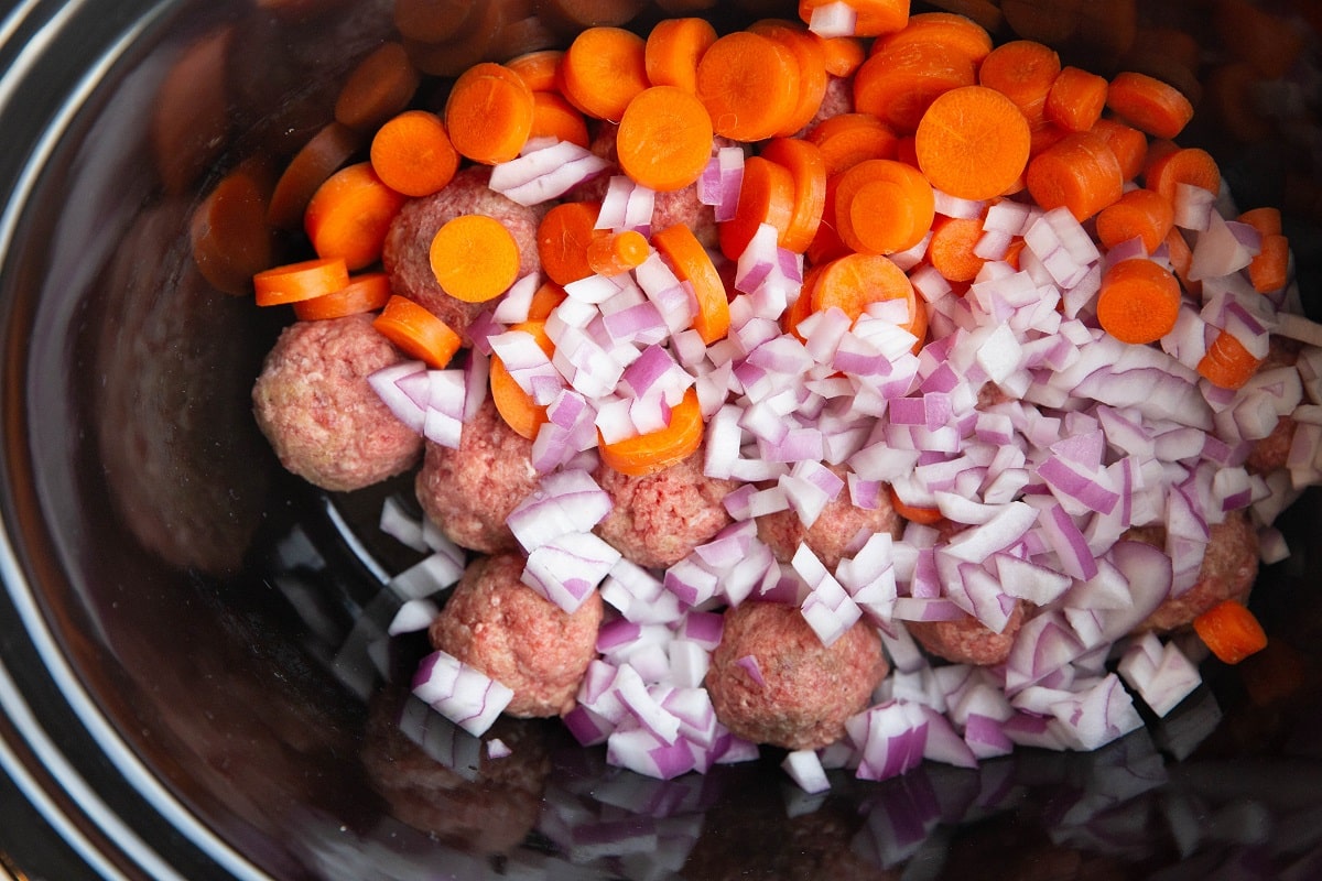 Carrots, onions, and meatballs in a crock pot.