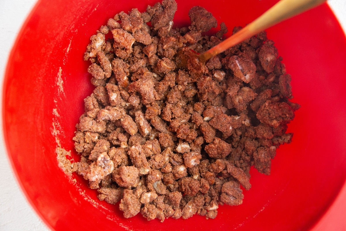 Red mixing bowl with pecan streusel topping inside.