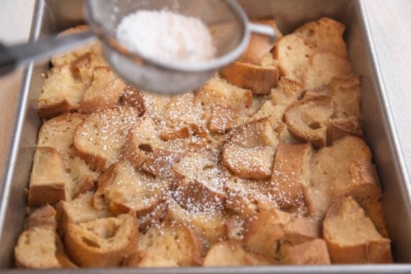 Sprinkling powdered sugar over the bread pudding