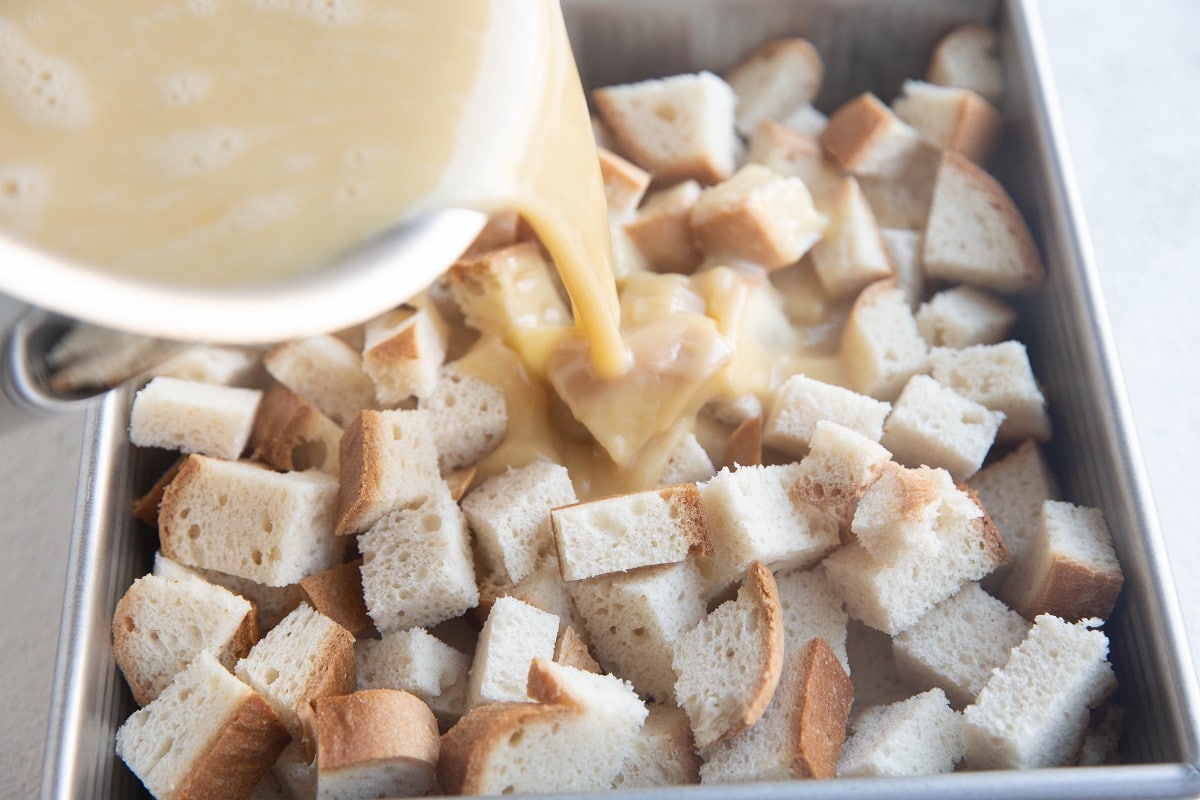 Pouring custard mixture over chunks of bread.