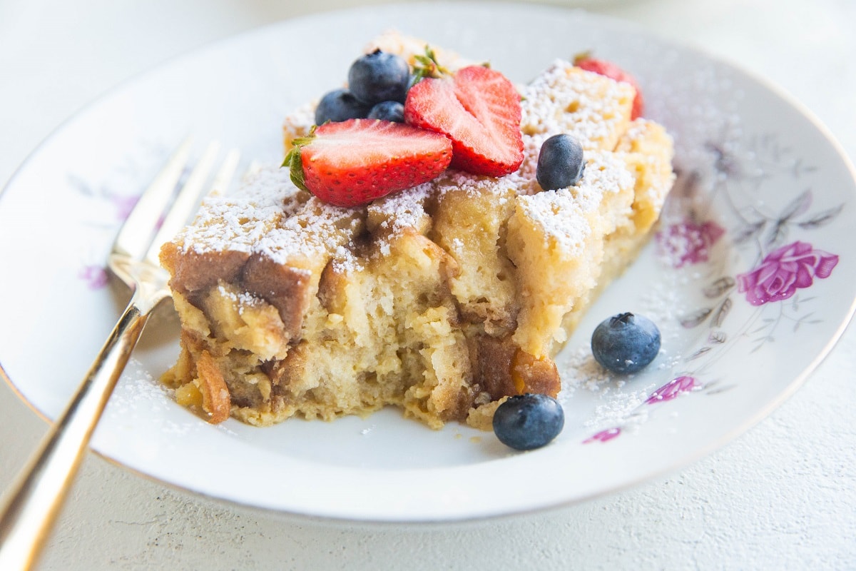 Slice of bread pudding in a bowl with a bite taken out so you can see the texture of the inside.