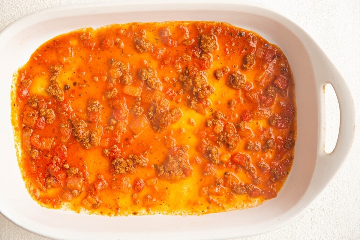 Tomato sauce spread on the bottom of a casserole dish.