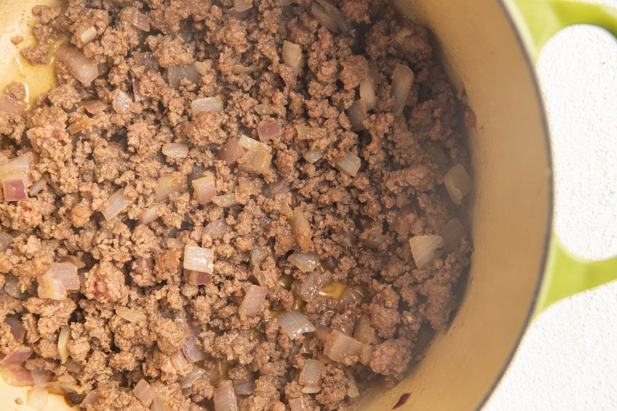 Ground beef cooking in a pot with onions and garlic to make meat sauce for lasagna