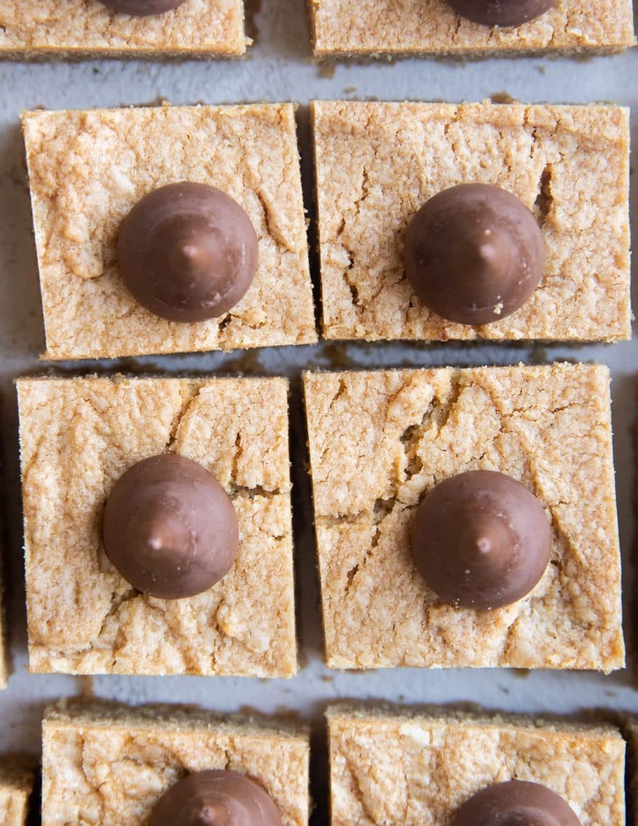 Top down photo of Peanut Butter Blossom Cookie bars cut into squares on a white background.