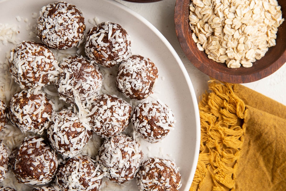 Horizontal image of chocolate peanut butter energy bites rolled in coconut sitting on a plate.