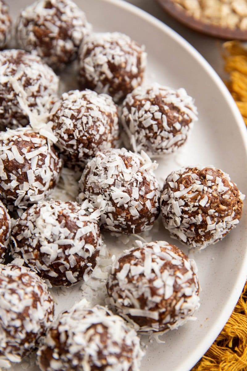 Angled shot of chocolate energy bites rolled in coconut on a plate.