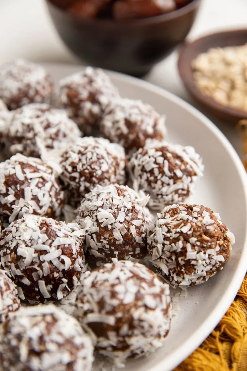 Close up angled shot of coconut rolled chocolate balls on a plate