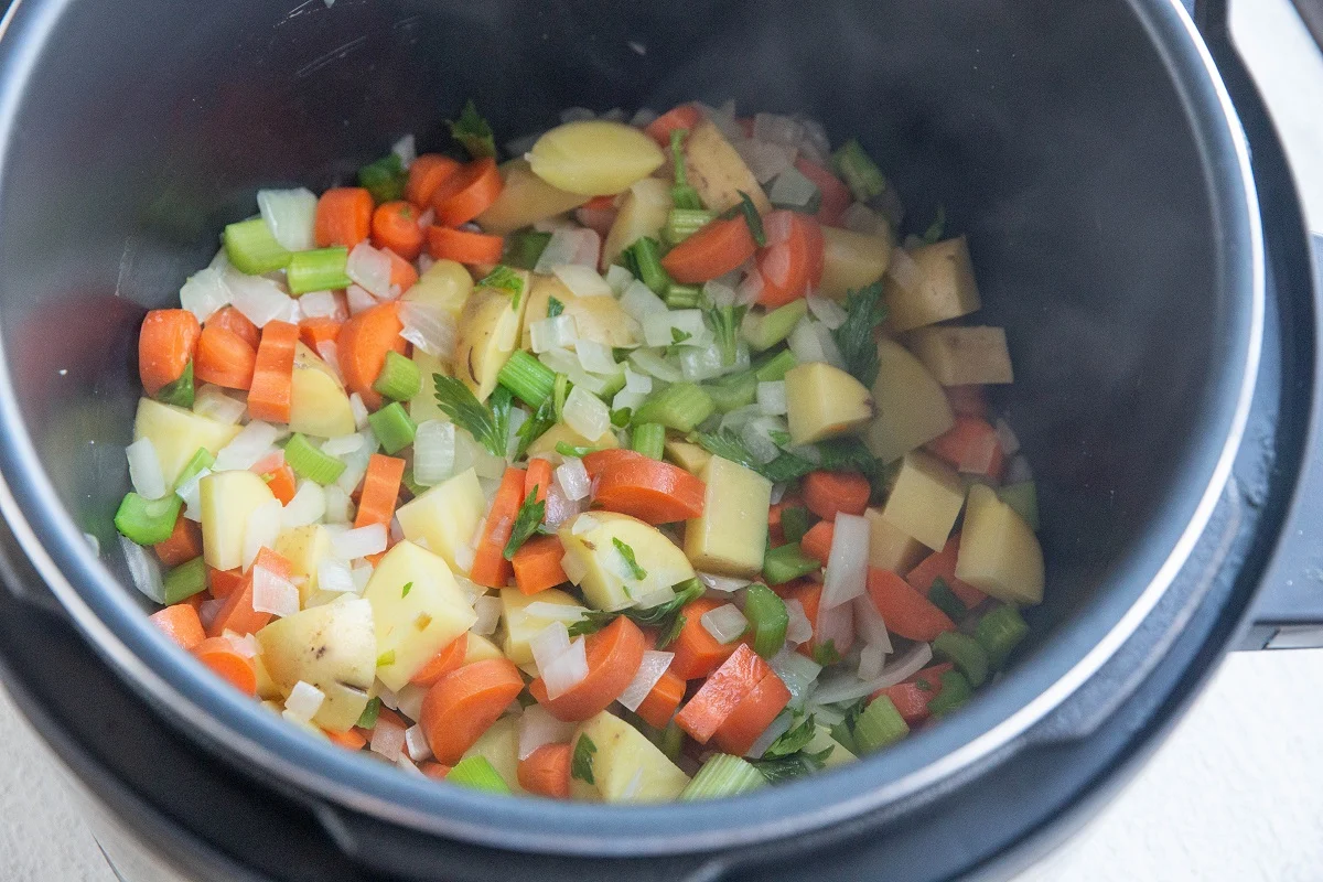Onion, garlic, carrots, celery, and Yukon gold potatoes cooking in an Instant Pot