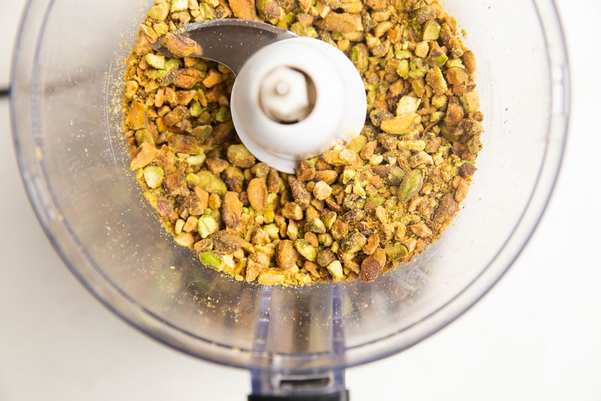 Food processor with chopped pistachios.