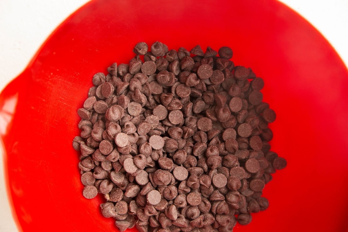 Chocolate chips in a red mixing bowl, ready to be microwaved.