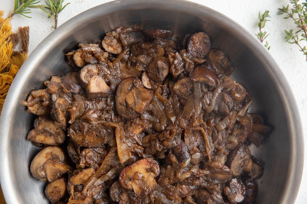 Stainless steel skillet with caramelized onions and mushrooms.