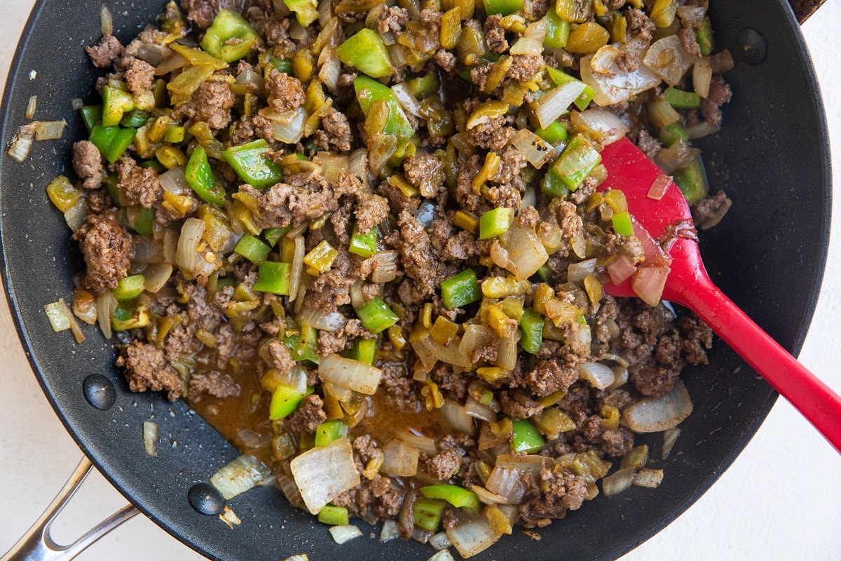 Meat for taco casserole cooking in a skillet, ready to transfer to the casserole dish.