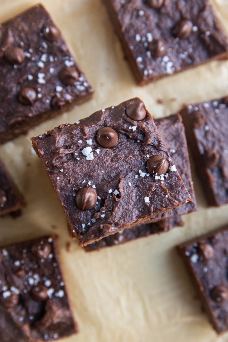 Slices of brownies sitting on a sheet of parchment paper, sprinkled with sea salt.