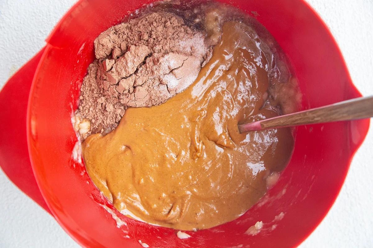 Mashed banana, peanut butter, and cocoa powder in a mixing bowl, ready to be mixed together.