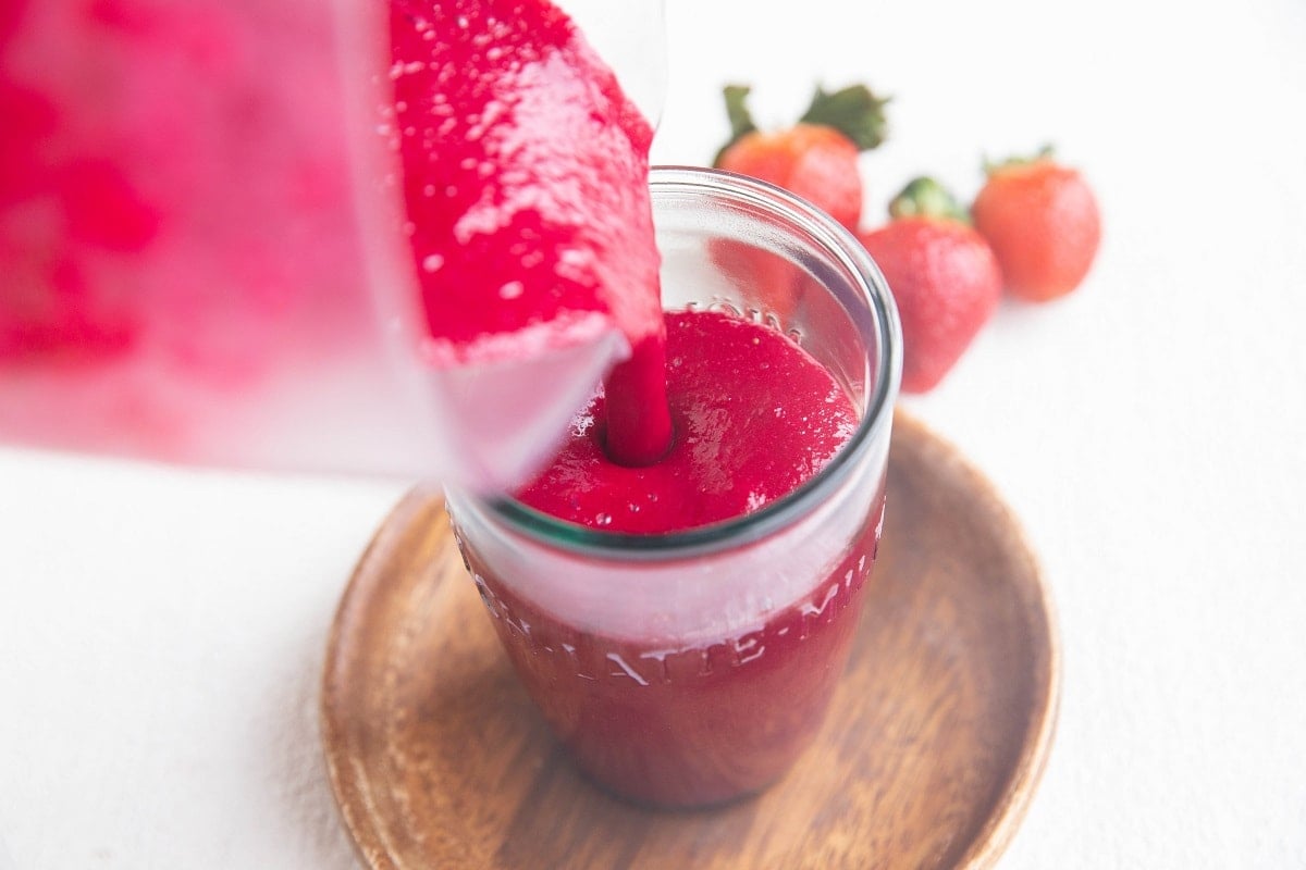 Pouring a smoothie into a glass from a blender.