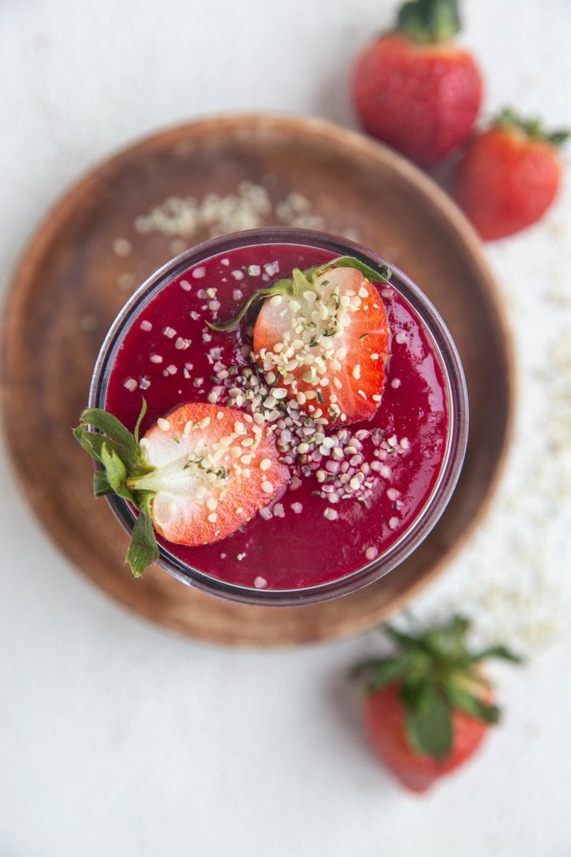 Beautiful beet smoothie on a white background with fresh strawberries to the side.