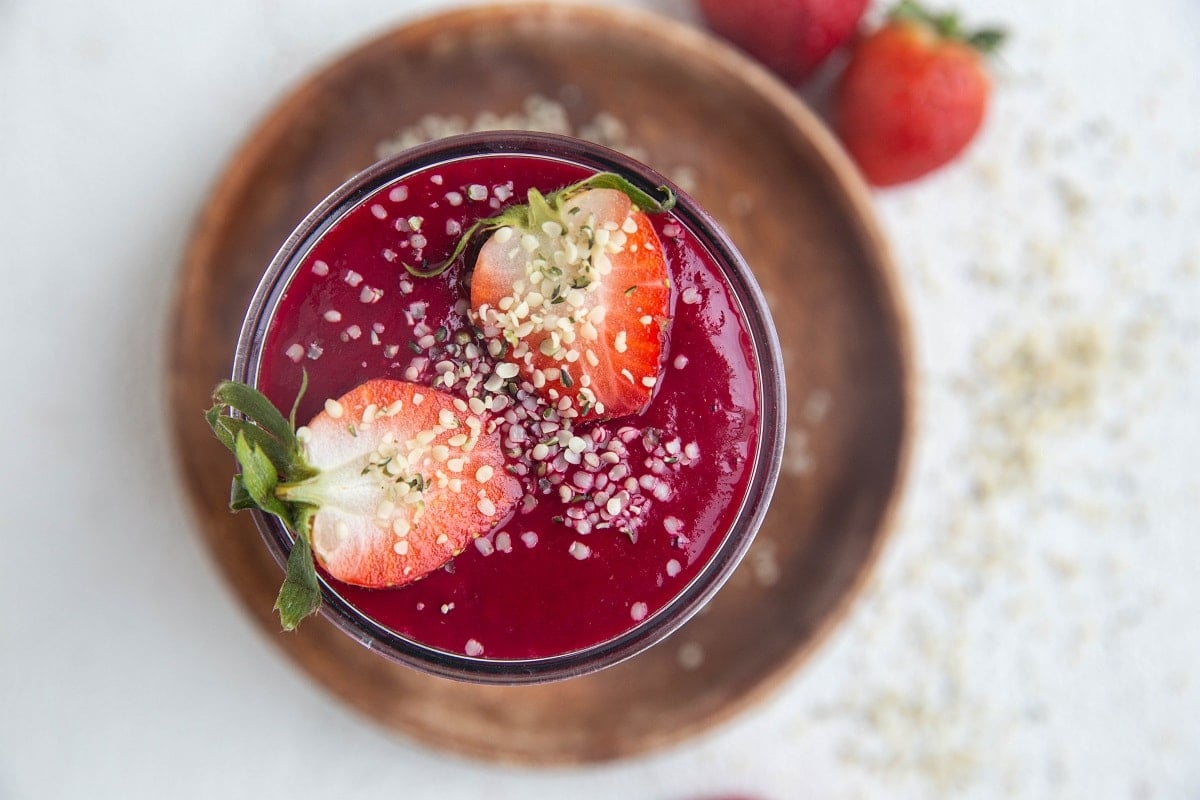 Horizontal image of beet smoothie with hemp seeds sprinkled on top.