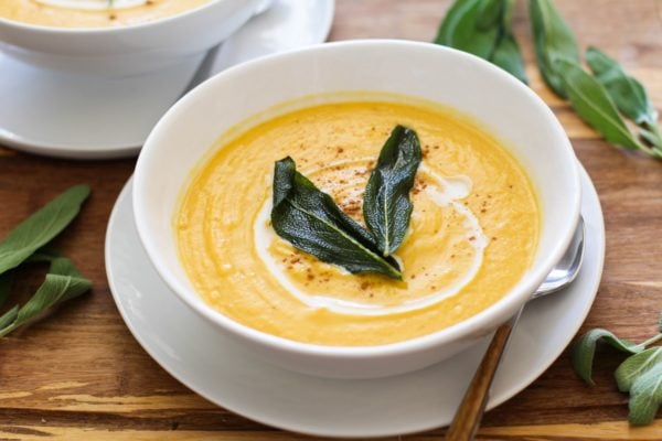 Horizontal image of butternut squash soup in a bowl with crispy sage on top.