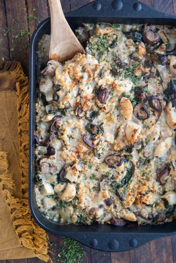 Large cast iron casserole dish full of chicken, rice, mushrooms, and creamy sauce.