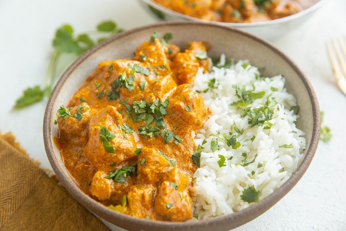 Horizontal image of a bowl of chicken tikka masala with white rice.