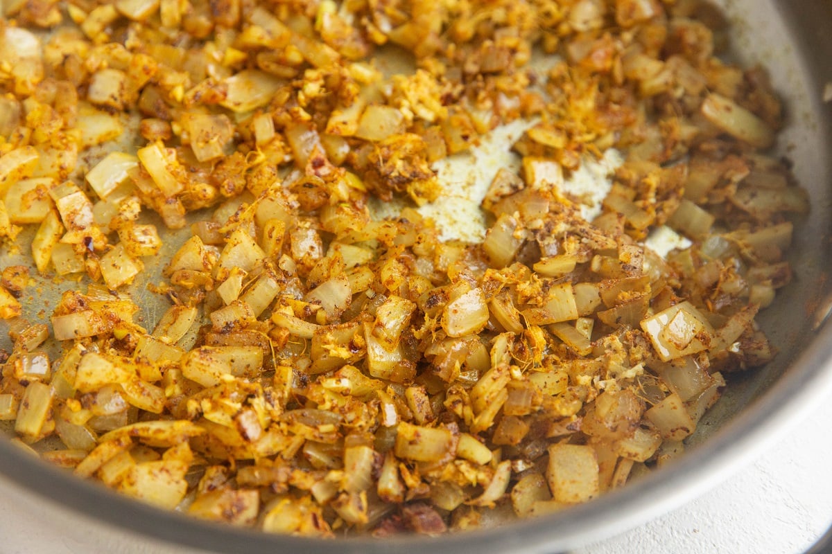 Onions and spices mixed together in a skillet.