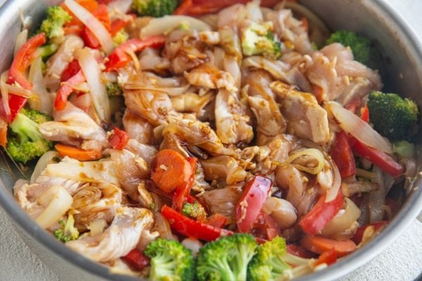 Chicken stir fry cooking in a skillet with coconut aminos or teriyaki sauce added in.