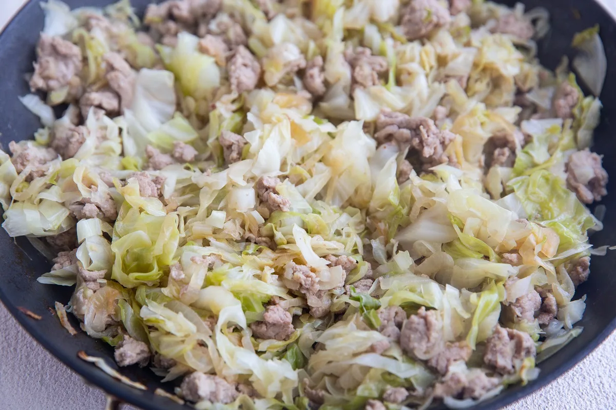 Ground turkey, cabbage, and onion cooking in a skillet.