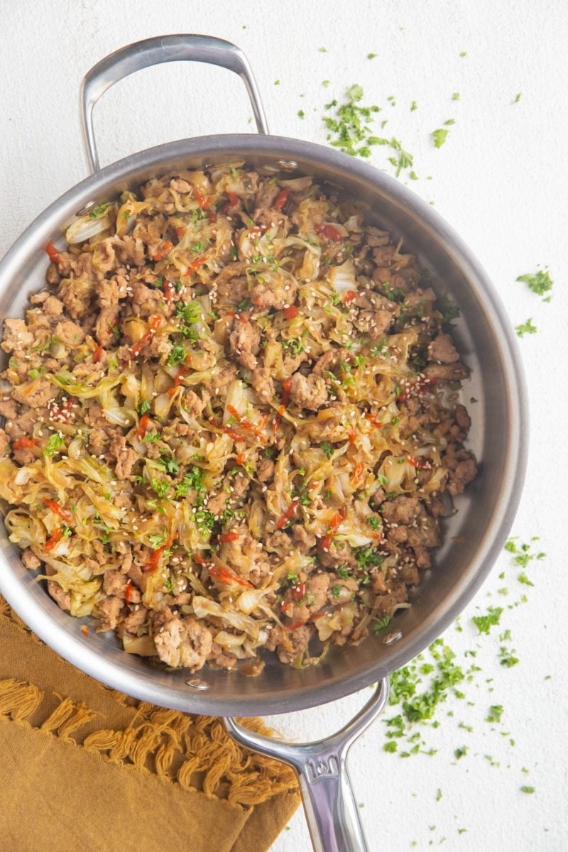 Stainless Steel Skillet of ground turkey, onions, cabbage, hot sauce, and fresh parsley, ready to serve.