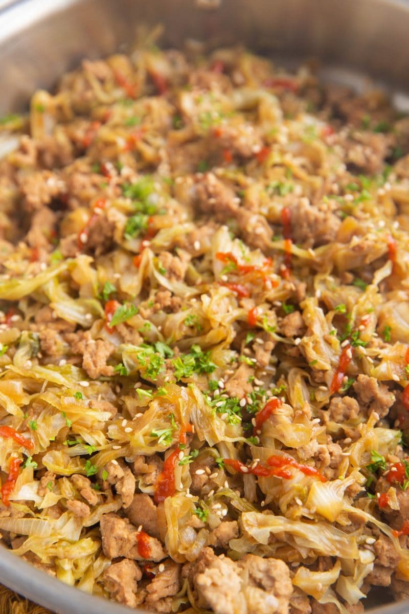 Close up on cooked ground turkey, caramelized onions and cabbage in a skillet.