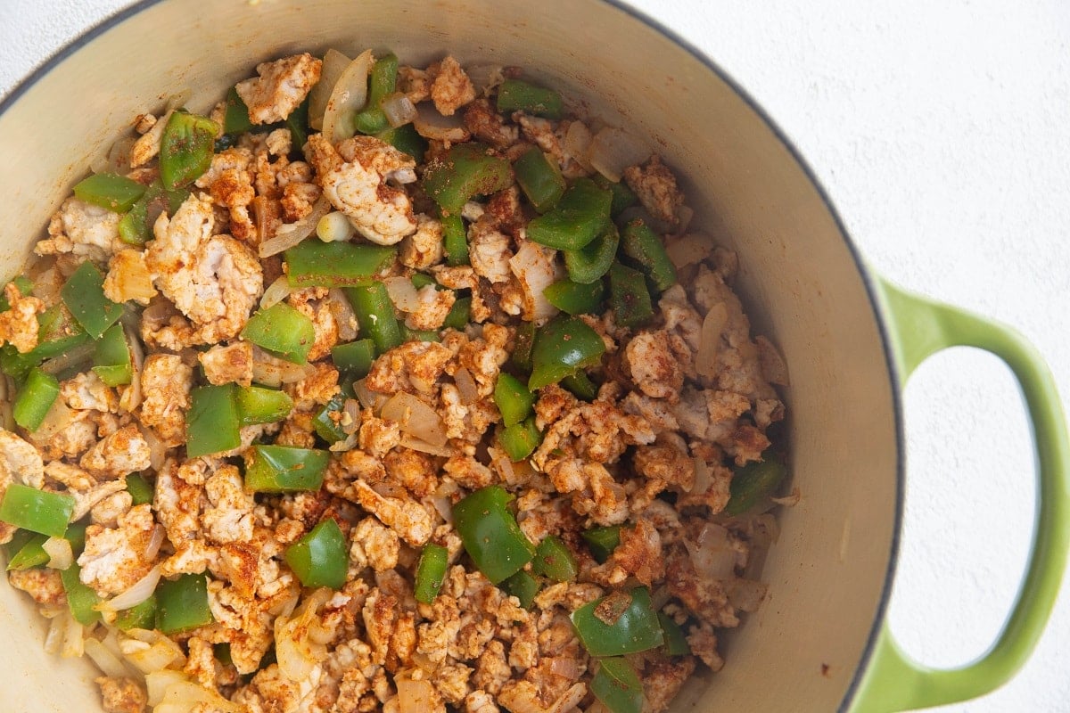 Onion, bell pepper, ground turkey and spices cooking in a large stock pot.