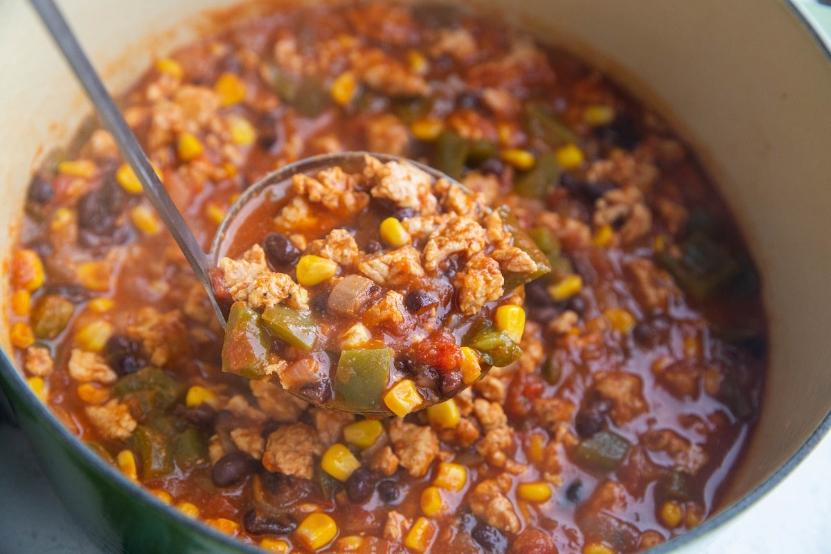 Pot of ground turkey taco soup with a ladle scooping some out.