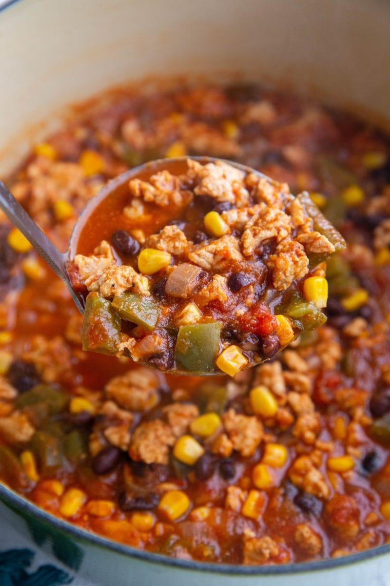 Large pot of ground turkey taco soup with a ladle serving a scoop of soup.