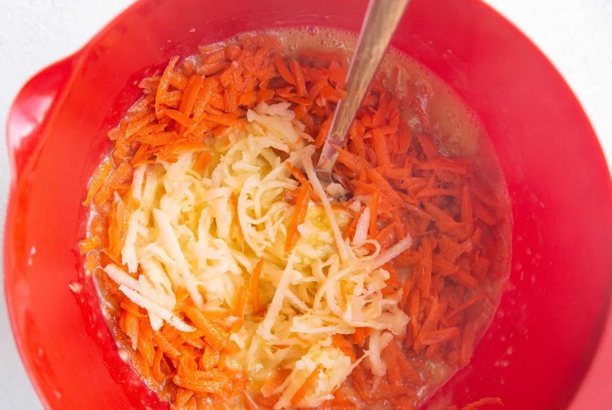 Grated apple and grated carrot on top of the wet ingredients, ready to be mixed in.