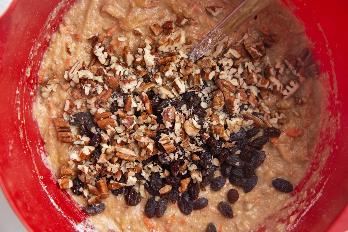 Raisins and chopped pecans on top of the morning glory muffin batter, ready to be mixed in.