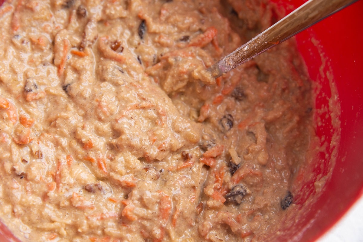 Morning glory muffin batter mixed up in a red mixing bowl, ready to bake